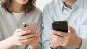 スマートフォンを一緒に見つめ、穏やかに微笑む40代の日本人男女。高画質で詳細に描かれた[ブライダルネットのレビュー]のイメージ画像で、誠実で落ち着いた大人の出会いを表現しています。