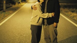 夜の道で静かに抱き合う40代男女の写真。女性はカジュアルなニットを着用。華の会メールのレビュー記事で、サクラの真偽や地方での出会い方について解説するイメージ。