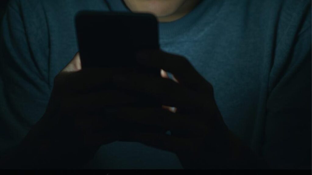 スマホ画面を深刻な表情で見つめる男性。マッチングアプリの日記で避けるべきネガティブな発言や、自慢話などのNG投稿をしていないか確認する慎重な姿勢。