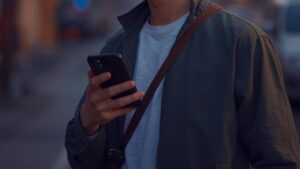 PCMAXのレビュー記事のアイキャッチ画像。落ち着いた雰囲気の40代男性が、夕暮れの中でスマートフォンを操作している様子を写した自然な写真。