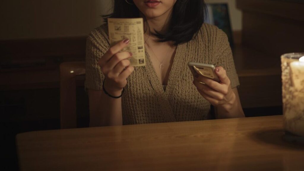 夜の自宅デスクで、旅行の写真を見ながら新しい話題を思いつく30代後半の女性。マッチングアプリで付き合う前のLINEの頻度がマンネリ化するのを防ぐ日常。